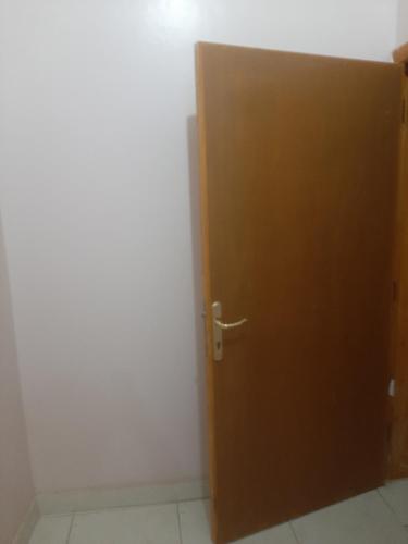 una puerta marrón en una habitación con una pared blanca en فله, en Ad Dawādimī