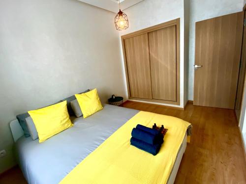 a bedroom with a bed with yellow and blue pillows at Appartement près de Novotel face au parc in Mohammedia