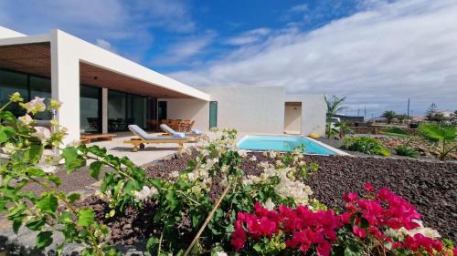 a house with a swimming pool and some flowers at Villa Sal Marina Deluxe Lajares in Lajares