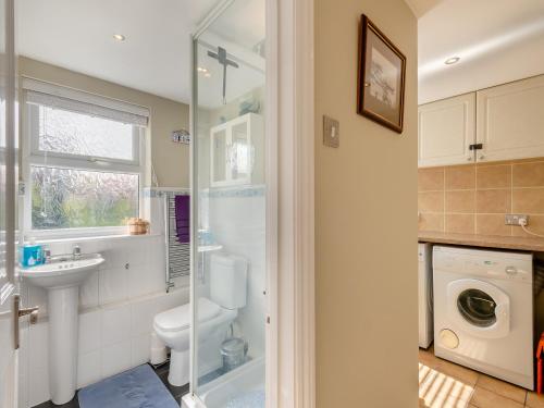 a bathroom with a toilet sink and a washing machine at Curlew Cottage in Caister-on-Sea