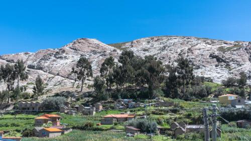 un petit village en face d'une montagne dans l'établissement Hostal Cultural Bertha Challapampa Isla del Sol parte Norte, à Comunidad Challapampa