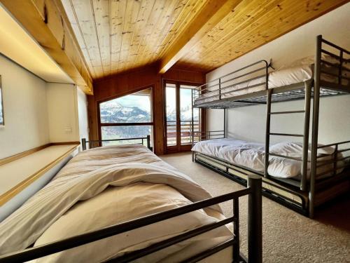 two bunk beds in a room with a window at Résidence Le Cristal - Chalets pour 8 Personnes 154 in Crest-Voland