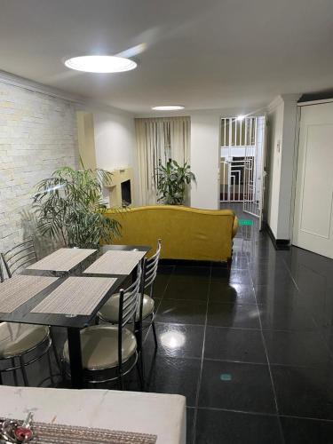 a dining room with tables and chairs and a yellow couch at Hospedaje la Estrella in Floridablanca