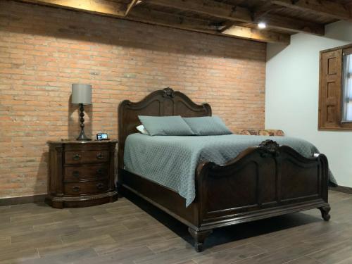 - une chambre avec un lit et un mur en briques dans l'établissement Cozy House en Mineral de Pozos, à Mineral de Pozos