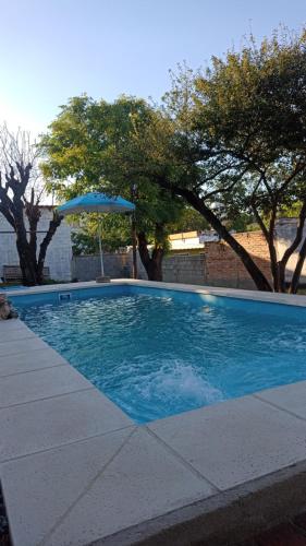 a blue swimming pool with an umbrella and trees at Chalet MAX in Bialet Massé