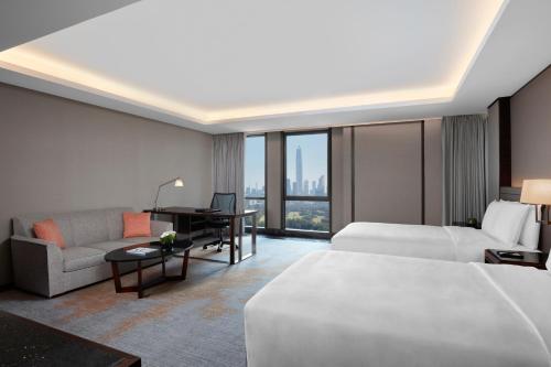 深セン市にあるJW Marriott Hotel Shenzhenのベッド、ソファ、デスクが備わるホテルルームです。