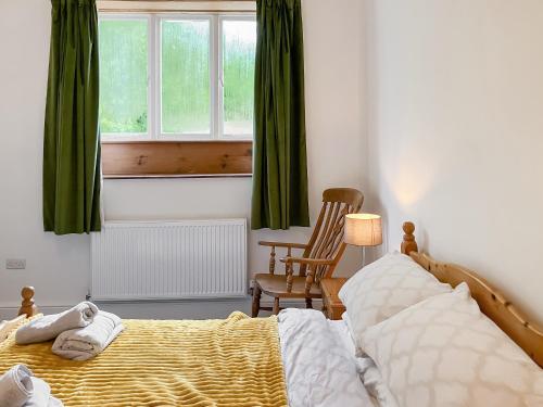 a bedroom with a bed and a chair and a window at Coldwell Street Cottage in Wirksworth