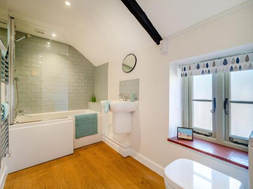 a bathroom with a tub and a toilet and a sink at Cherry Tree Cottage - Uk30237 in Great Snoring