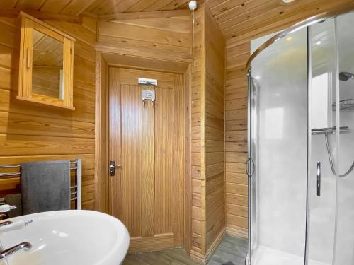 La salle de bains est pourvue d'un lavabo blanc et d'une douche. dans l'établissement Apple-uk46285, à Camerton
