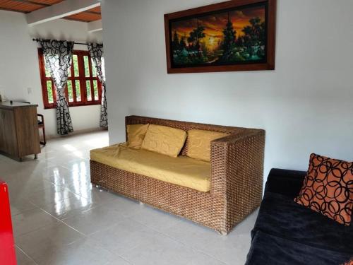 a wicker couch in a living room with a painting on the wall at Chalet La Estancia - Parque del Café in Montenegro