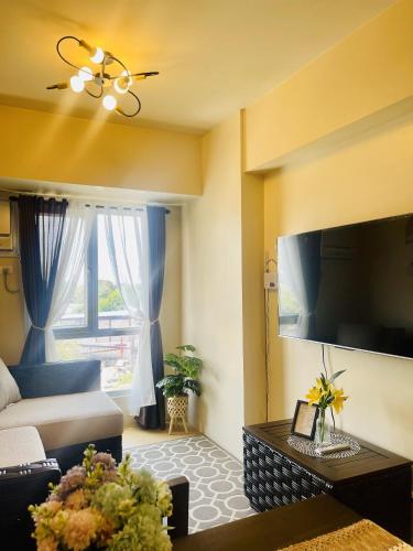 a living room with a couch and a large television at Sunset View 1-BR Unit at Centrio Tower beside Ayala Mall Downtown CDO in Cagayan de Oro
