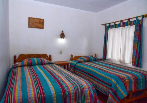 a bedroom with two beds and a window at Hostal Cultural Bertha Challapampa Isla del Sol parte Norte in Comunidad Challapampa