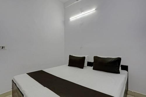 uma cama num quarto branco com almofadas pretas em OYO HOTEL KAVYA RESIDENCY em Alīgarh