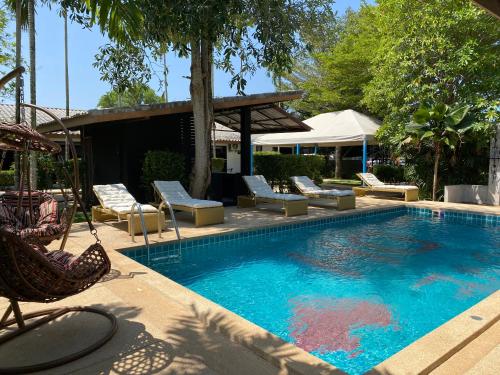 a swimming pool with chaise lounge chairs and a resort at Apollo Hotel Chalong in Ban Suan