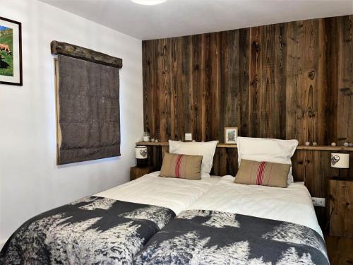 a bedroom with a large bed with a wooden wall at Résidence Stone Shed - 5 Pièces pour 8 Personnes 981 in Saint-Marcel