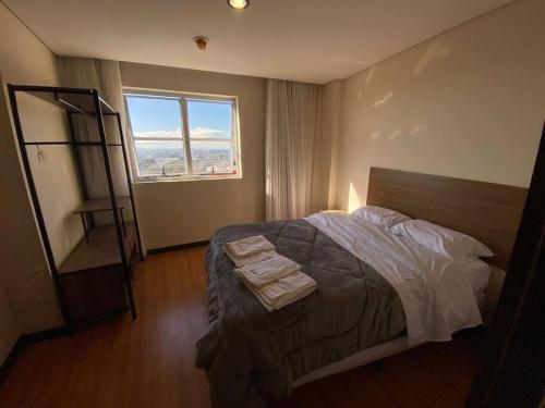 a bedroom with a bed and a large window at Flat 1 qto, piscina, loc central in São José dos Pinhais