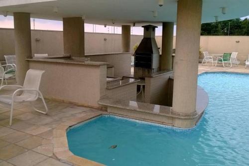 a swimming pool with a bar and a grill in a hotel at Flat 1 qto, piscina, loc central in São José dos Pinhais