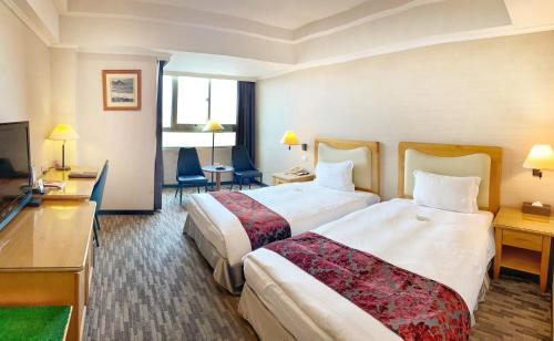 a hotel room with two beds and a television at Golden Tulip Zhong Xin Hotel Taichung in Taichung