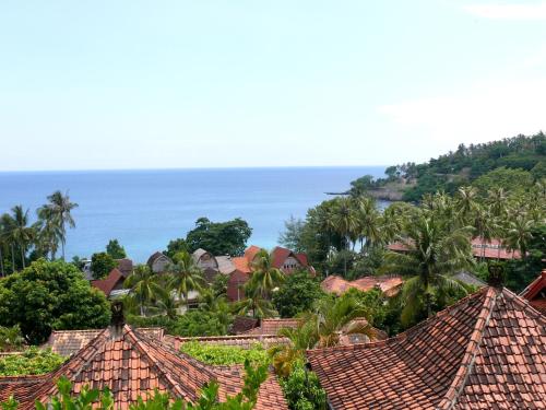 a group of houses with the ocean in the background at Puri Bunga Beach Cottages in Senggigi 