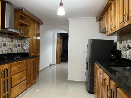 uma cozinha com armários de madeira e um frigorífico preto em Pacifica Hostel em Medellín
