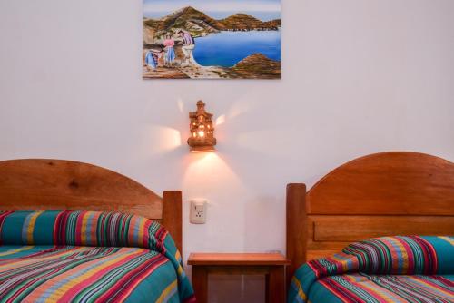 Habitación con 2 camas y una foto en la pared. en Hostal Cultural Bertha Challapampa Isla del Sol parte Norte en Comunidad Challapampa