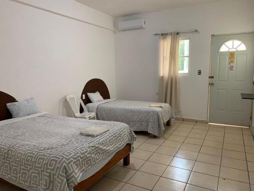 a room with two beds and a window and a door at HOTEL PUERTO REAL SUITES in Paraíso