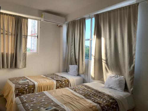um quarto de hotel com duas camas e uma janela em HOTEL PUERTO REAL SUITES em Paraíso