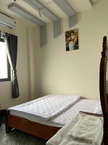 SAIGON - PLEIKU HOTEL في بلاي كو: غرفة نوم بسرير وصورة على الحائط