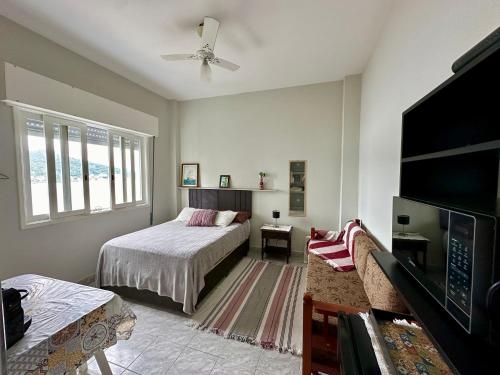 um quarto com uma cama e uma televisão num quarto em Kitnet pé na areia! Vista espetacular ! em São Vicente