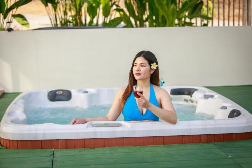 พรพนาฮิลล์รีสอร์ท في Ban Makok: امرأة جالسة في حوض الاستحمام عقد كوب من النبيذ