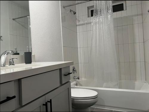 a white bathroom with a toilet and a tub and a sink at Banty Villa - Master Lounge in Austin