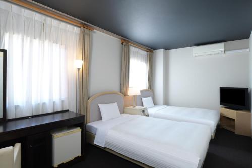 um quarto de hotel com duas camas e uma televisão em HOTEL MYSTAYS Miyazaki em Miyazaki