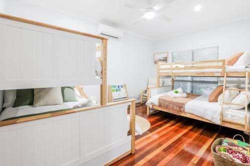 a bedroom with two bunk beds and wooden floors at Agnes Bliss - Stunning four-bedroom apartment in Agnes Water