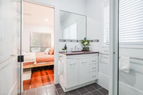 a white bathroom with a sink and a bed at Agnes Bliss - Stunning four-bedroom apartment in Agnes Water