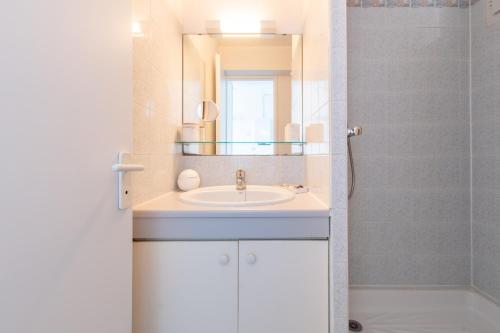 un bagno con lavandino e specchio di L'Evasion Bleue * WIFI * Bord de mer * Piscine * a Cap d'Agde