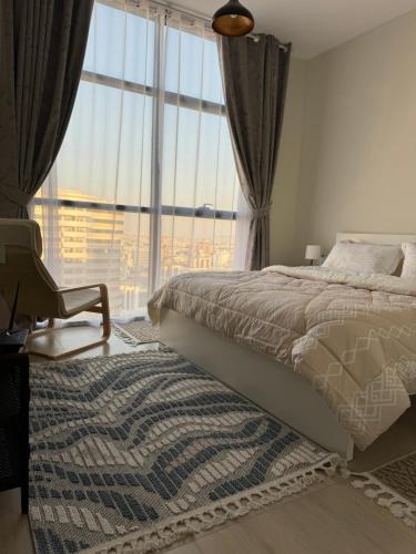 una camera da letto con un letto e una sedia e una grande finestra di sharja 1105 a Sharjah