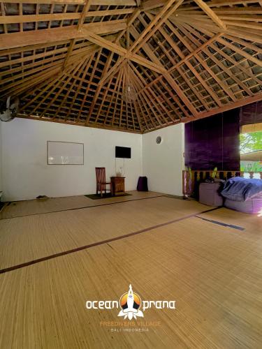 a large room with a wooden floor and wooden ceiling at Ocean Prana Village in Amed