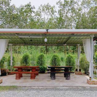 a pavilion with two picnic tables under it at บ้านชมดาวรีสอร์ทบึงโขงหลง in Ban Don Klang