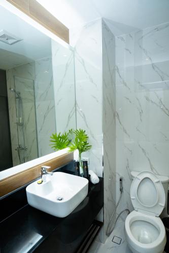 a white bathroom with a sink and a toilet at Amber Hotel - Cebu in Cebu City