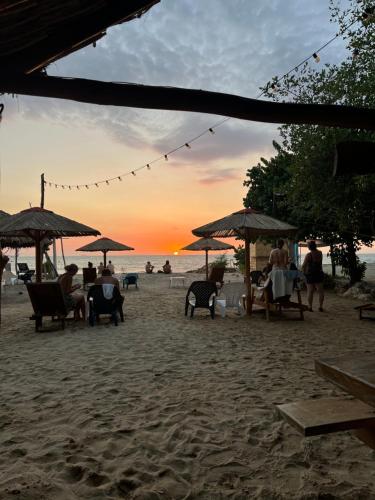 a group of people sitting under umbrellas on a beach at Hostel Beach House in Rincón