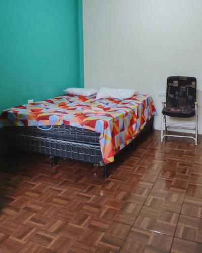 Cette chambre comprend un lit avec une couverture colorée et une chaise. dans l'établissement Casa el callejón, à San Pedro de la Laguna