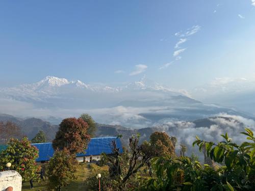 vista sulle montagne con un edificio blu e gli alberi di Club ES Deurali Resort a Pokhara