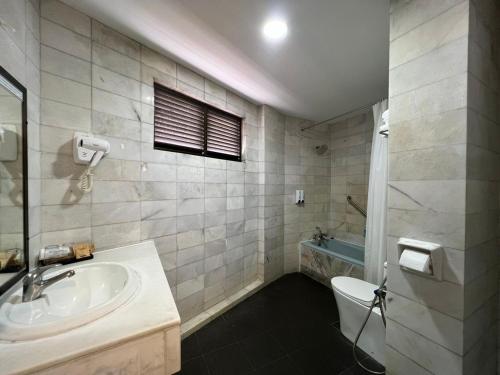 a bathroom with a sink and a toilet and a tub at Remington Hotel in Muar