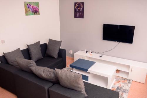 Unity homes #G08 في إلدوريت: غرفة معيشة مع أريكة سوداء وتلفزيون
