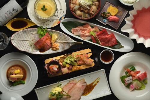 una mesa con muchos platos de comida. en Kami no yama Azumaya, en Kaminoyama