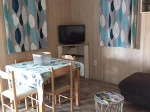 un salon avec une table, des chaises et une télévision dans l'établissement Chalet 2 chambres au calme avec piscine chauffée, proche lac et plages en Vendée - FR-1-783-20, à La Chapelle-Hermier