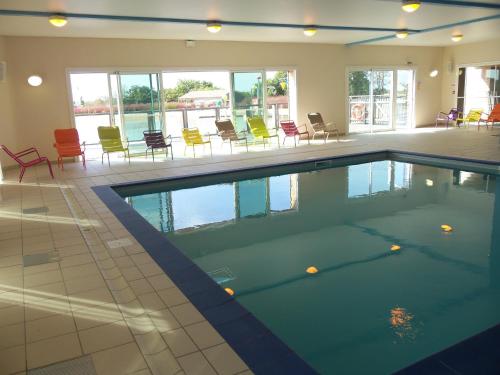- une piscine avec des tables et des chaises colorées dans l'établissement Chalet 2 chambres au calme, piscine chauffée, près du lac du Jaunay et plages de Vendée - FR-1-783-10, à La Chapelle-Hermier