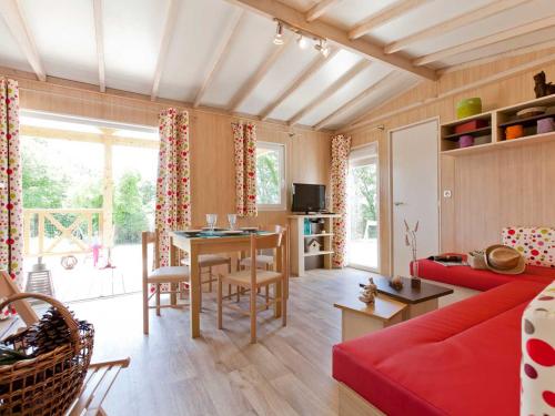 ein Wohnzimmer mit einem roten Sofa und einem Tisch in der Unterkunft Chalet familial au calme avec piscine près du lac du Jaunay, proche plages et activités. - FR-1-783-21 in La Chapelle-Hermier