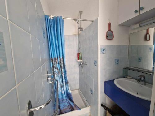 ein Badezimmer mit einem blauen Duschvorhang und einem Waschbecken in der Unterkunft Appartement Marseillan-Plage, 2 pièces, 4 personnes - FR-1-326-815 in Marseillan