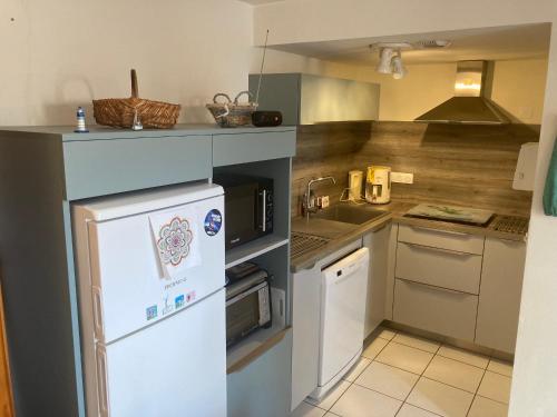 Il comprend une petite cuisine équipée d'un réfrigérateur blanc et d'appareils électroménagers. dans l'établissement Maison avec piscine, proche forêt et plage à Saint Jean de Monts - FR-1-323-527, à Saint-Jean-de-Monts